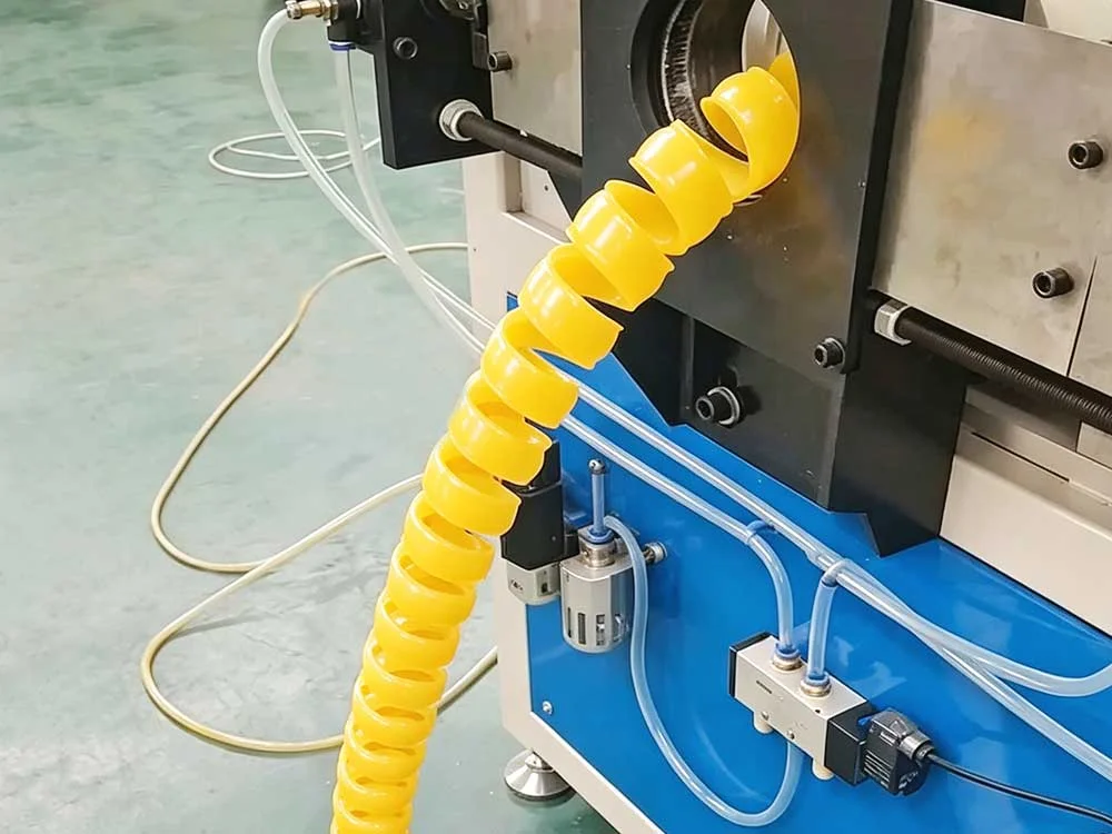 Proteção em espiral amarela para mangueiras a ser submetida a controlo de qualidade durante o fabrico